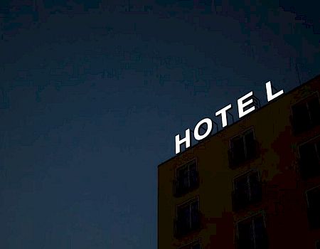 The image shows the side of a building with the sign "HOTEL" at night, partially visible against the dark sky.