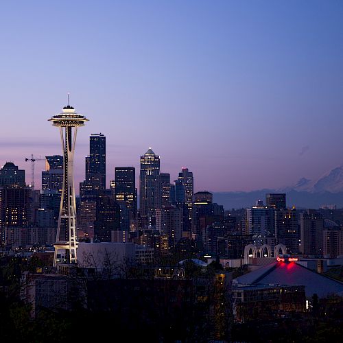 This image shows the Seattle skyline at dusk, featuring the Space Needle and Mount Rainier in the background.